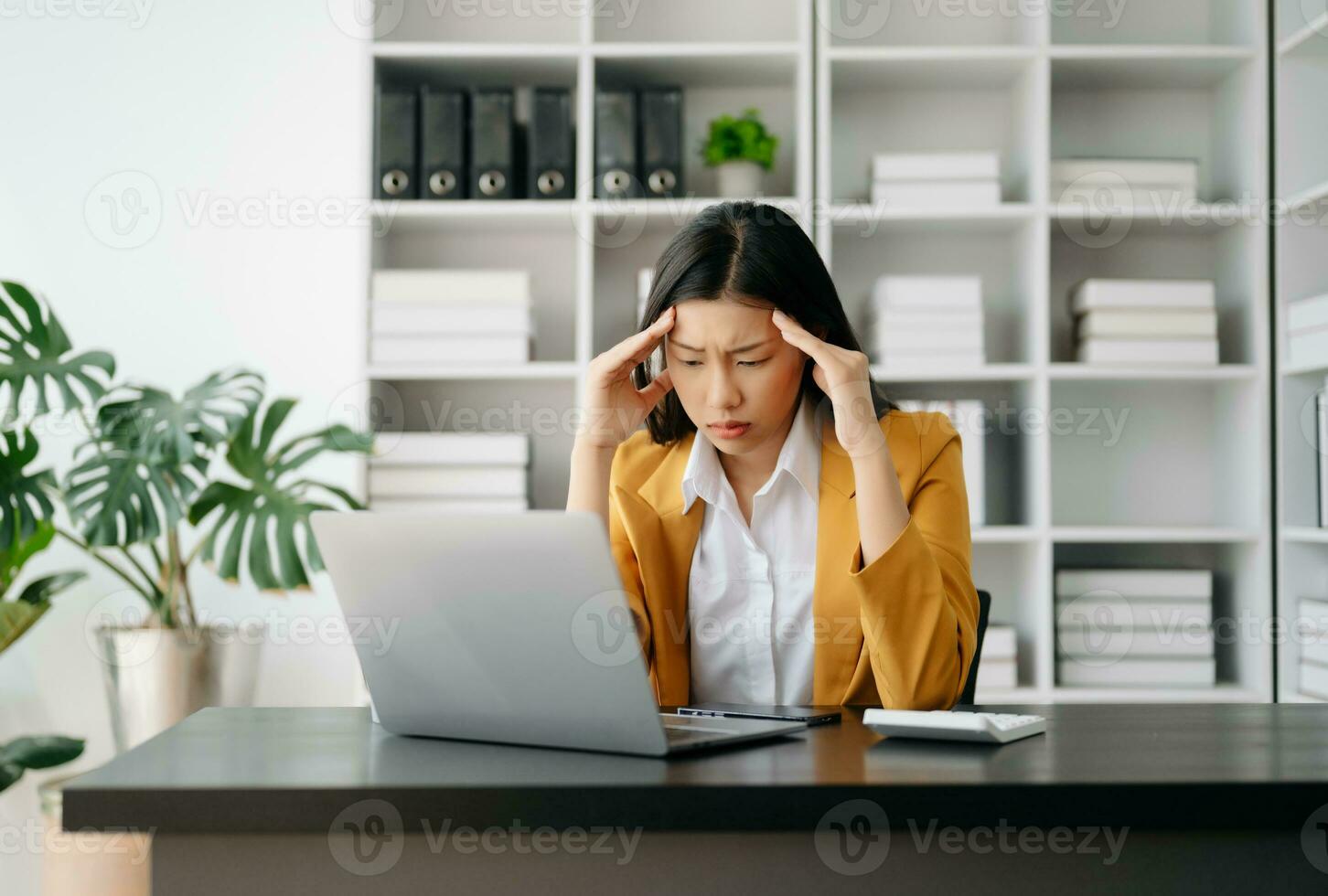 Asian business woman is stressed, bored, and overthinking from working on a tablet at the modern office. photo