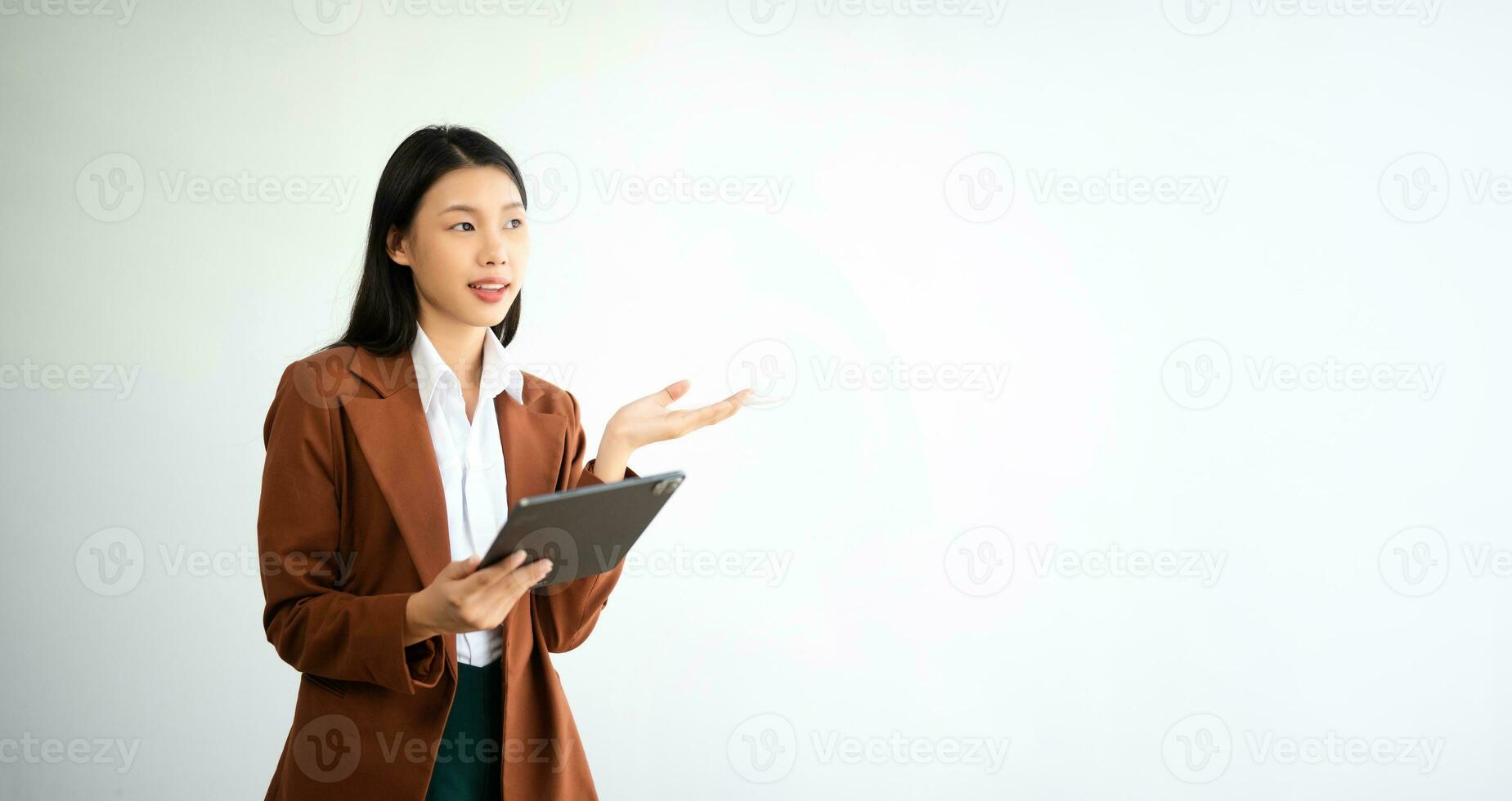 Portrait photo of young beautiful Asian woman feeling happy and holding smart phone, tablet and laptop with black empty screen on white background product presenting concept.