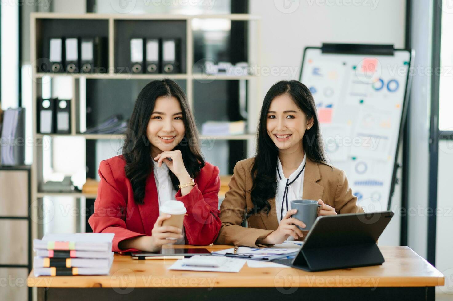 tipo líder ejecutivo gerente compartir y discutir negocio soluciones plan ideas en tableta con asiático hembra márketing gerente en oficina. foto