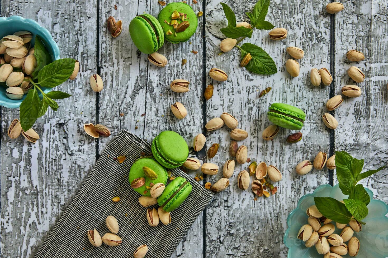 Green color pistachio macarons with pistachios on gray wooden background photo