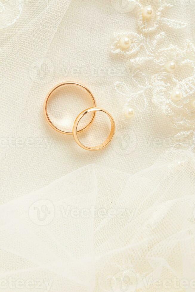 A chic vertical feed for two gold wedding rings on a beige satin background and lace tulle. space for text. layout design. photo