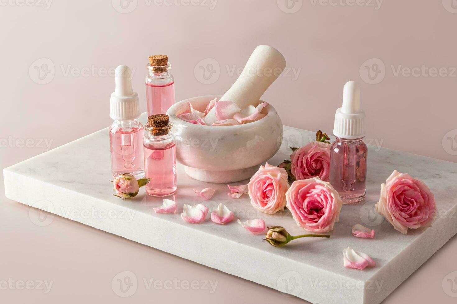 un conjunto de natural productos cosméticos para cara y cuerpo piel cuidado establecido en Rosa petróleo en varios botellas y un mortero con un mano de mortero y Rosa pétalos mármol podio. foto