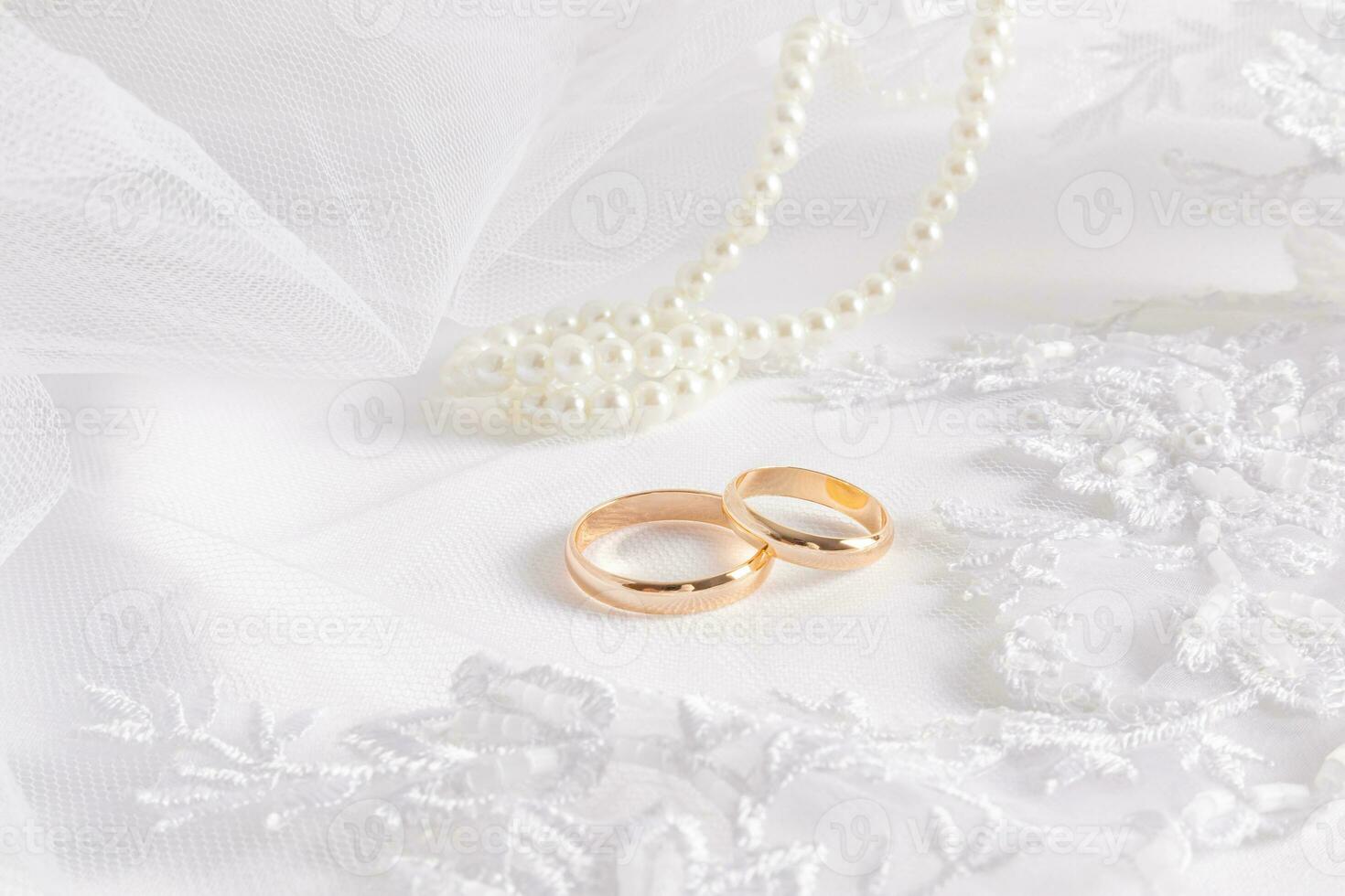 exquisite white airy lace bridal veils, two gold wedding rings and pearl beads. front view. Wedding background. The layout of the invitation. photo