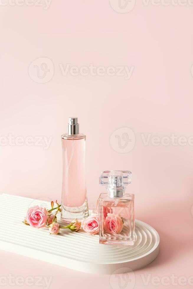 dos hermosa botellas de De las mujeres perfume o eau Delaware perfume en un blanco podio con pequeño rosado rosas. frente vertical vista. un Copiar espacio. foto