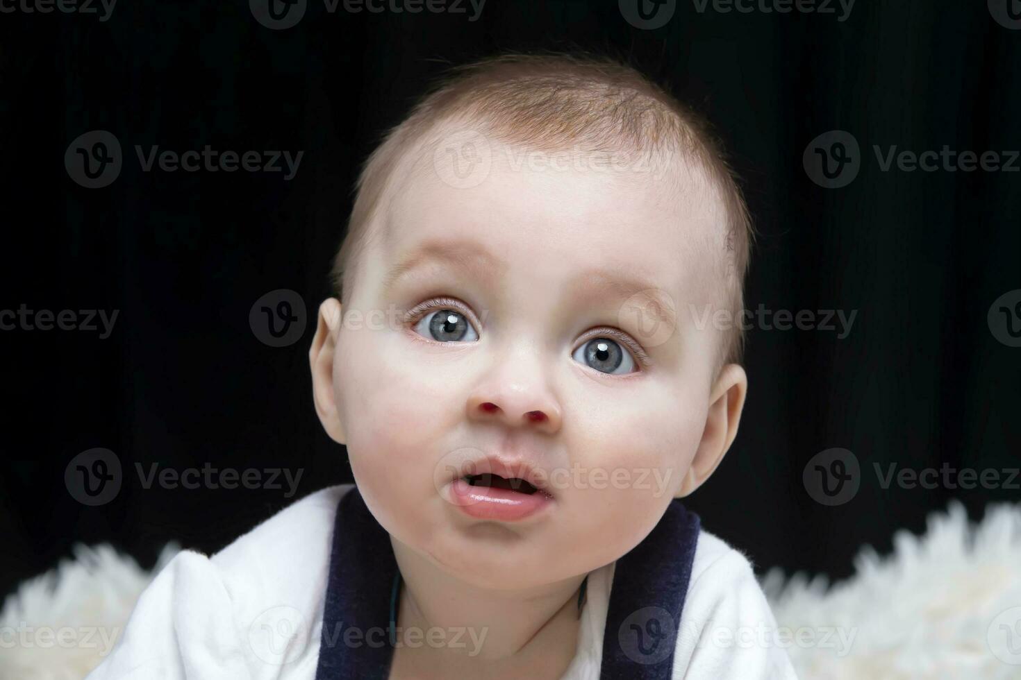 A beautiful kid looks at the camera in surprise. Baby at four months old. A funny child. photo