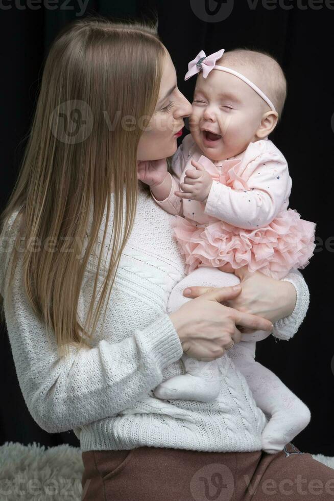 mamá sostiene su pequeño hija en su brazos. maternidad. foto