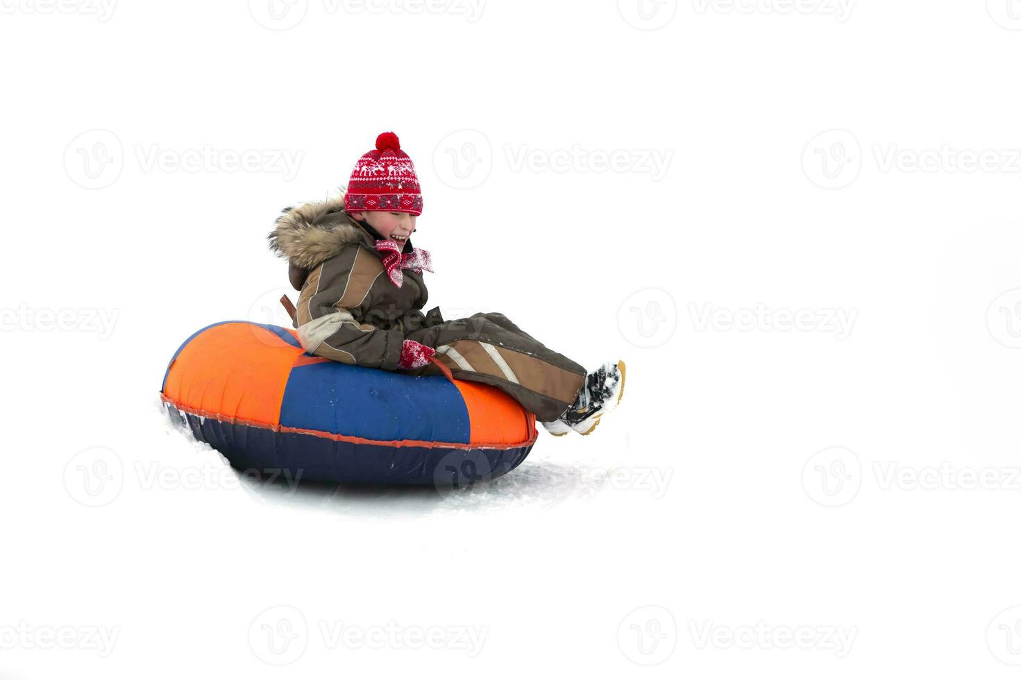 Child in winter. Cheerful boy is riding an inflatable sled. photo
