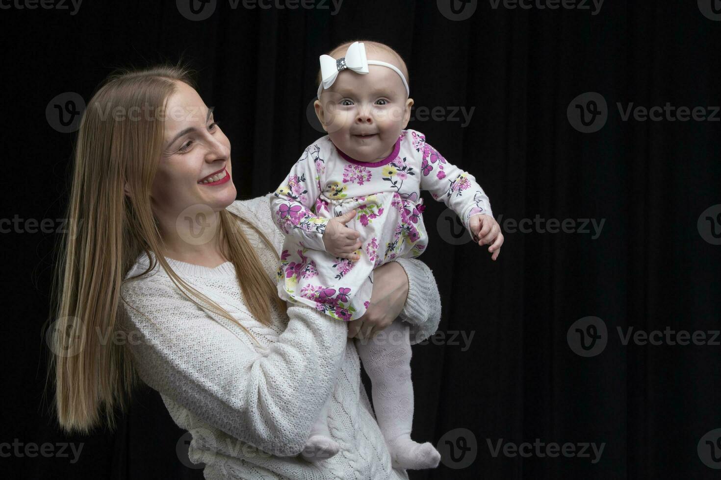 Mom holds a little happy daughter in her arms. Motherhood. photo