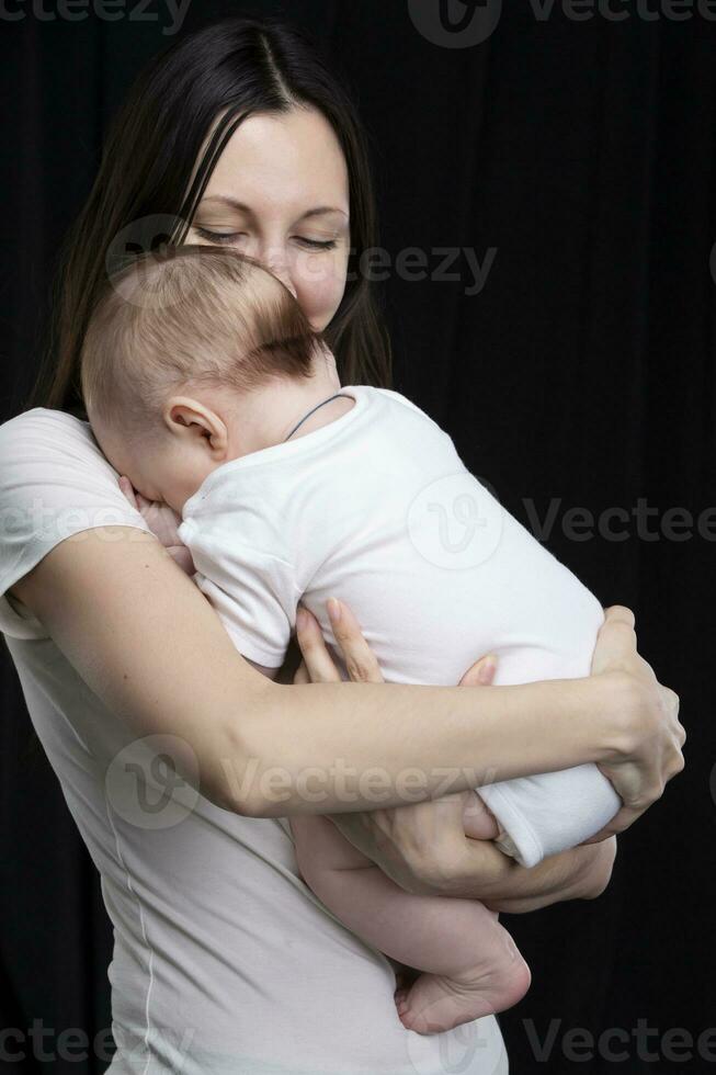 hermosa madre abrazos su bebé. maternidad.mamá y pequeño hijo en un oscuro antecedentes. maternidad. foto