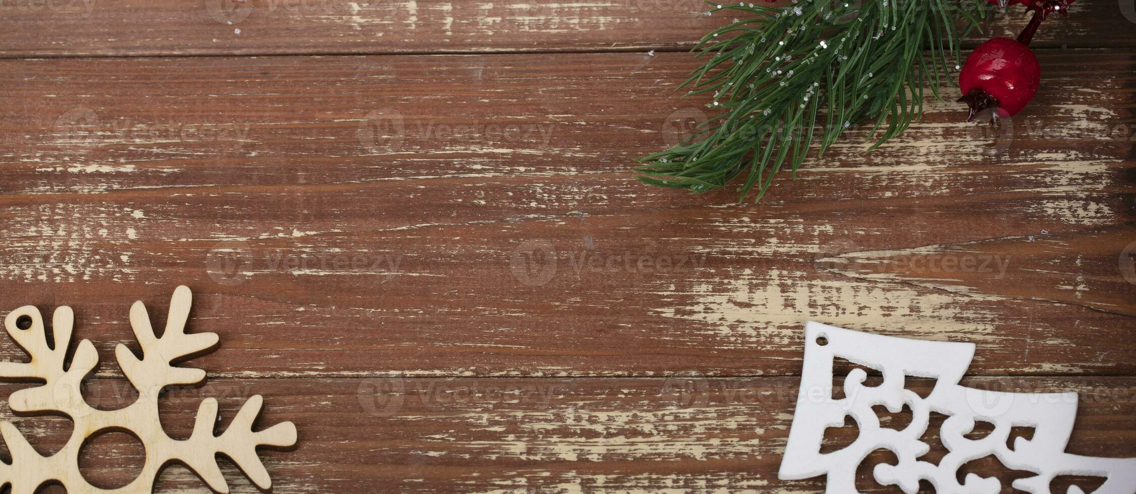 On a wooden background, a toy wood tree, a snowflake and a decoration of a fir branch and cones. Christmas background. photo