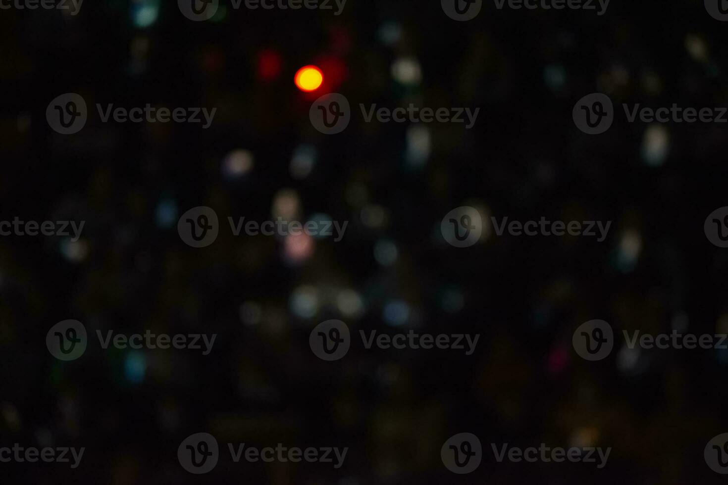 Black background with multicolored blurred bokeh spots and a bright yellow spot. photo