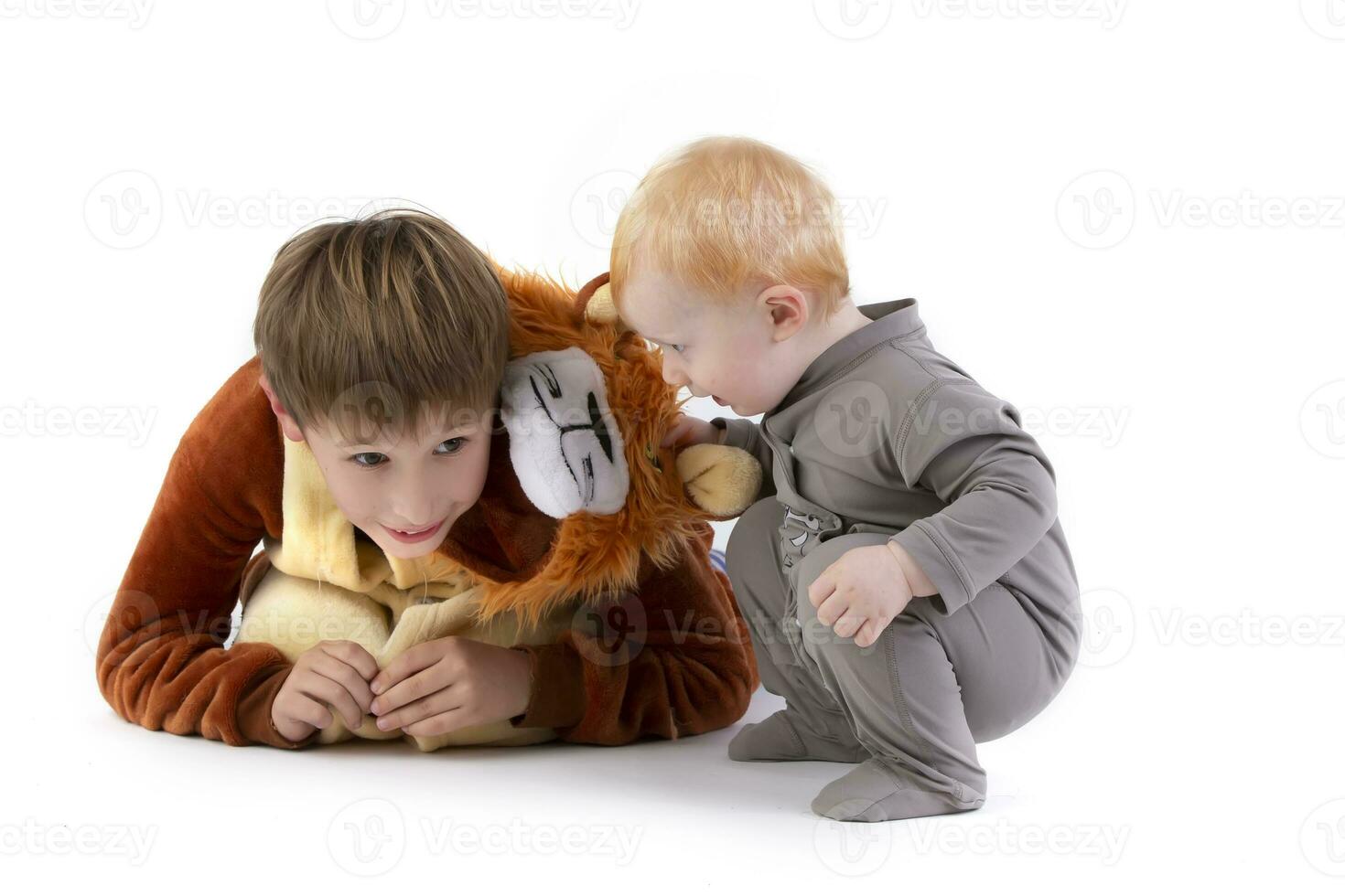 On a white background, the kid plays with his brother, dressed in a carnival lion costume. Elder and younger brother play. Funny kids. photo