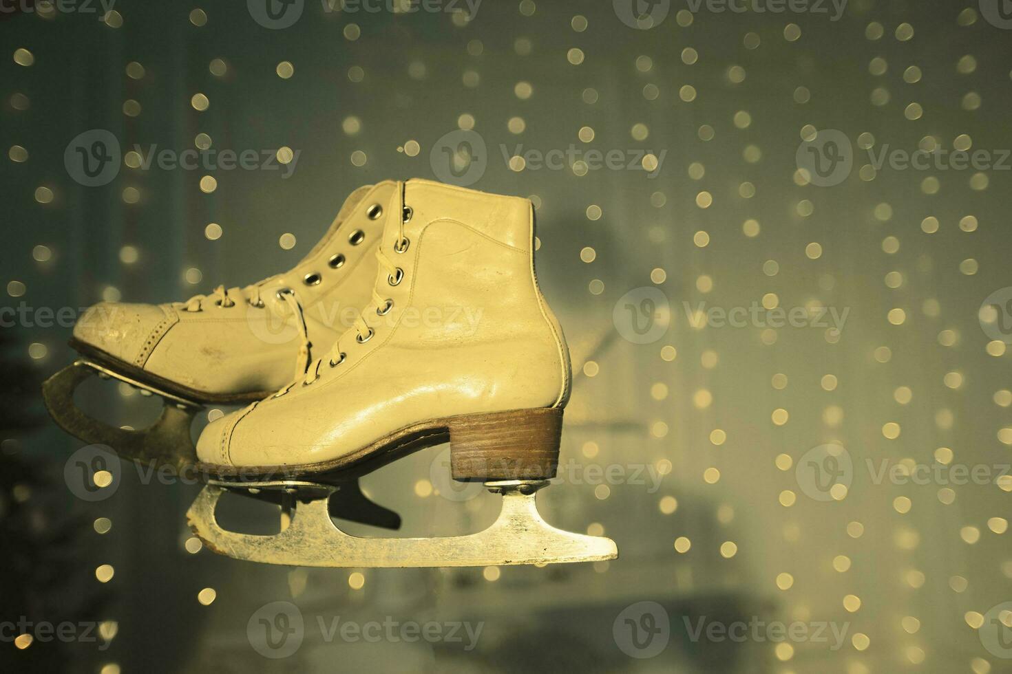 Vintage ice skates on faded green background with bokeh spots. photo