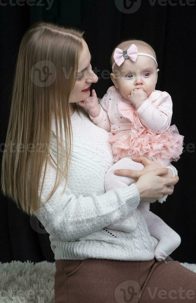 mamá sostiene su pequeño hija en su brazos. maternidad. foto