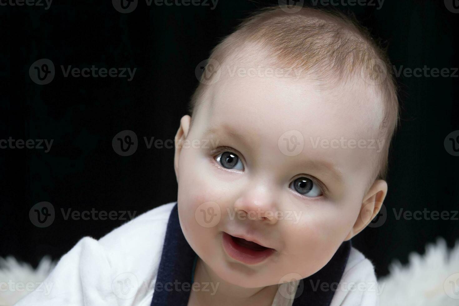 Beautiful baby boy smiles and looks into the camera. Baby at four months old. A funny child. photo