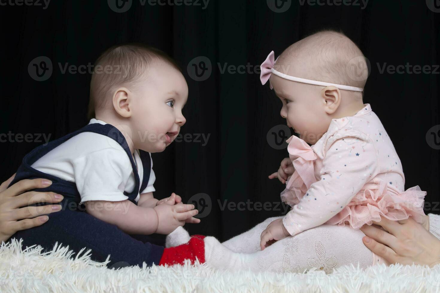 Funny little boy and girl are sitting opposite each other. Brother and sister kids. Children under one year old. photo