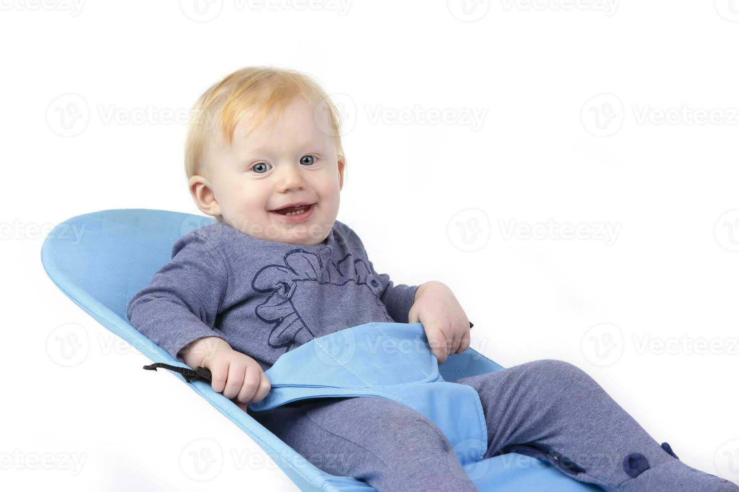 Over white background happy kid in a baby lounger sits and smiles. The boy is one year old. photo
