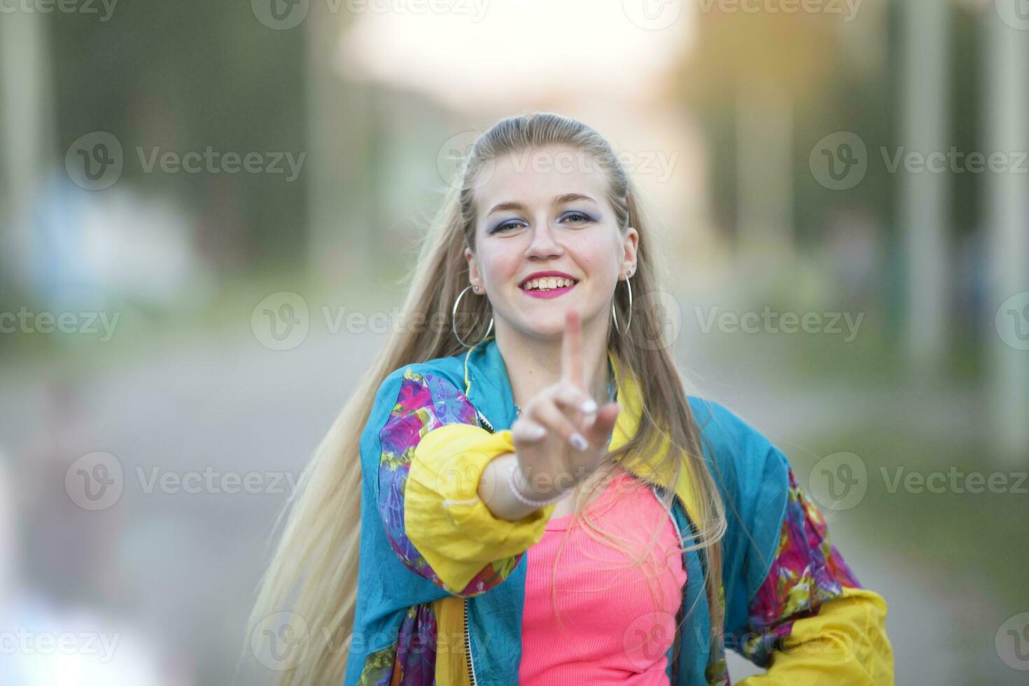 Beautiful blonde girl dressed in the style of the nineties dancing on the street. photo