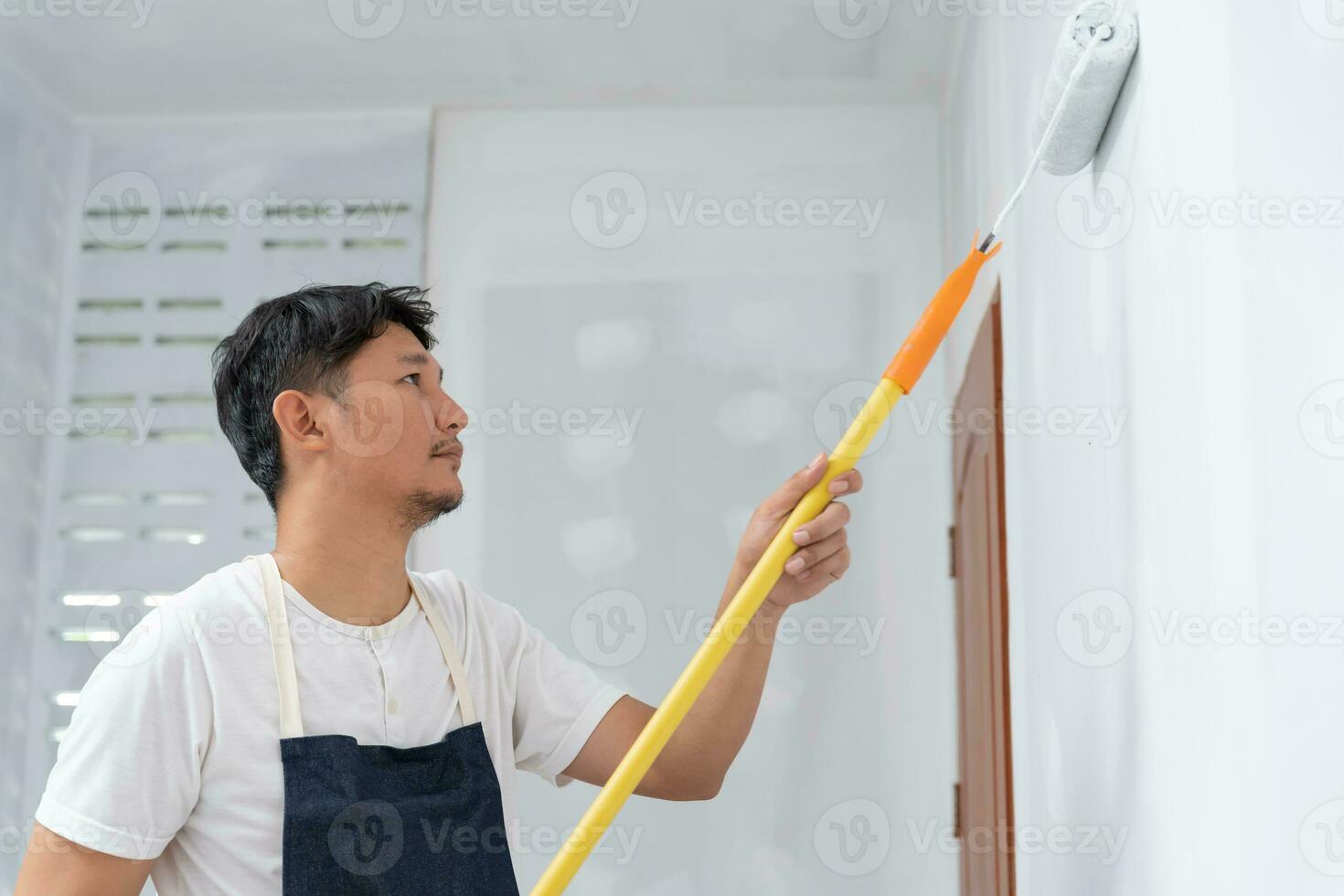 painter man, brush in hand for products to restore and paint the wall, indoor the building site of a house, wall during painting, renovation, painting, contractor, Architect, construction worker photo