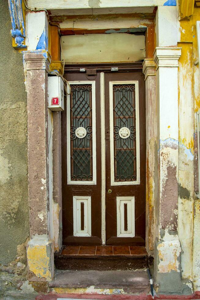 A wooden double door, with dark brown windows with a stone wall. photo