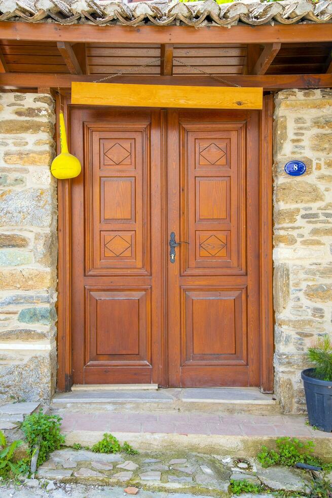 A wooden double door, with dark brown windows with a stone wall. photo