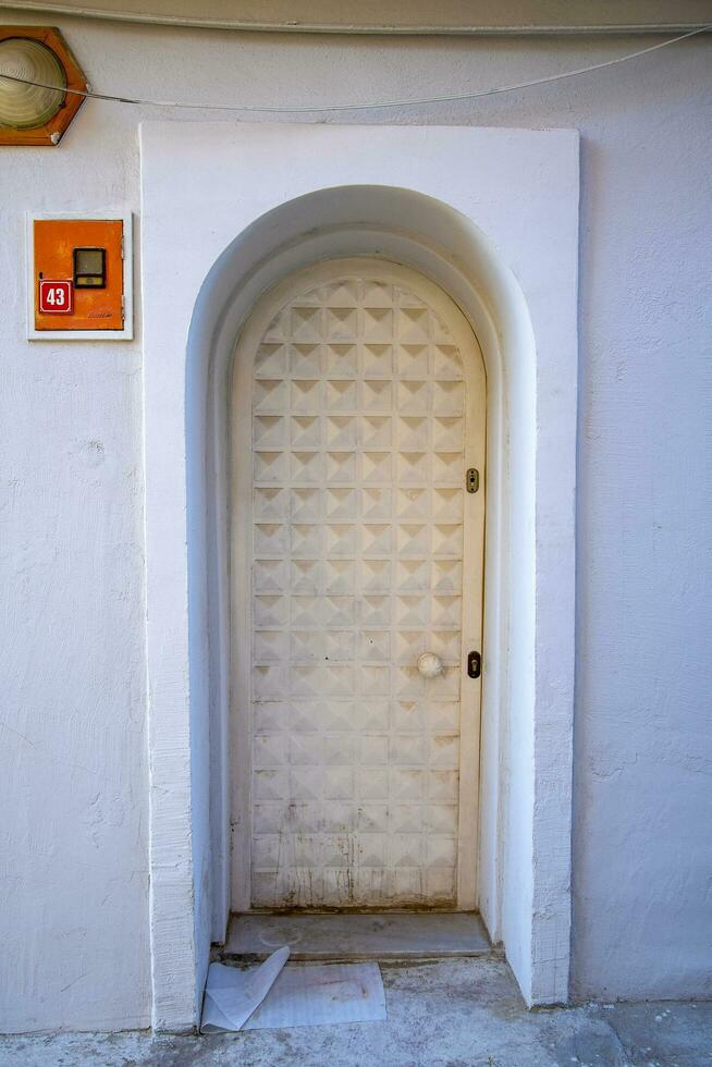 A white narrow door in a Turkish house with an arch and a window. photo