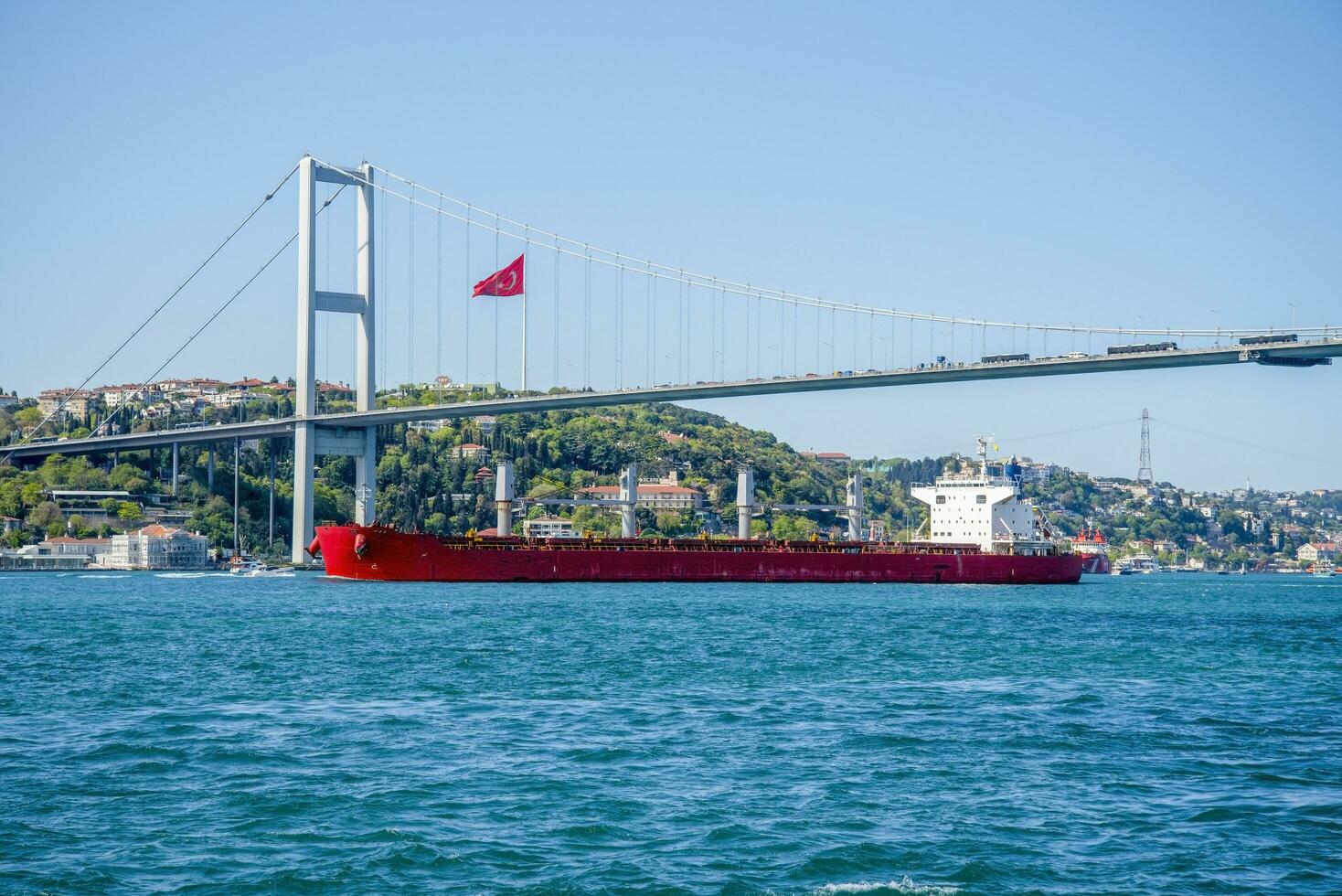 A cargo ship sails under a bridge in Istanbul on a summer and sunny day. photo