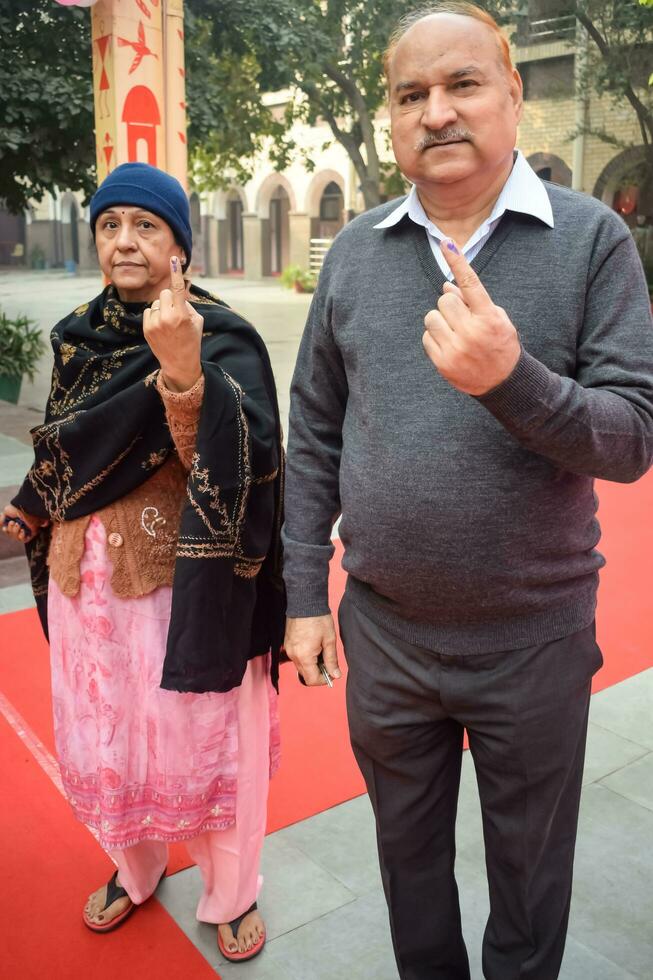 New Delhi, India - March 04 2023 - Unidentified people showing their ink-marked fingers after casting votes in front of polling booth of east Delhi area for MCD local body Elections 2022 photo