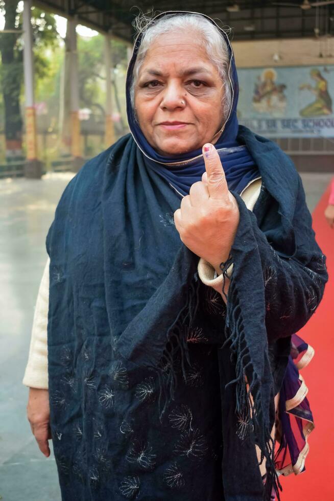 New Delhi, India - March 04 2023 - Unidentified people showing their ink-marked fingers after casting votes in front of polling booth of east Delhi area for MCD local body Elections 2022 photo