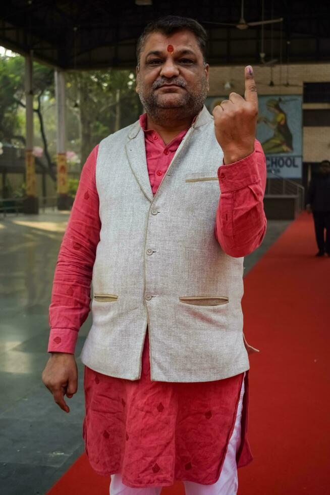 New Delhi, India - March 04 2023 - Unidentified people showing their ink-marked fingers after casting votes in front of polling booth of east Delhi area for MCD local body Elections 2022 photo