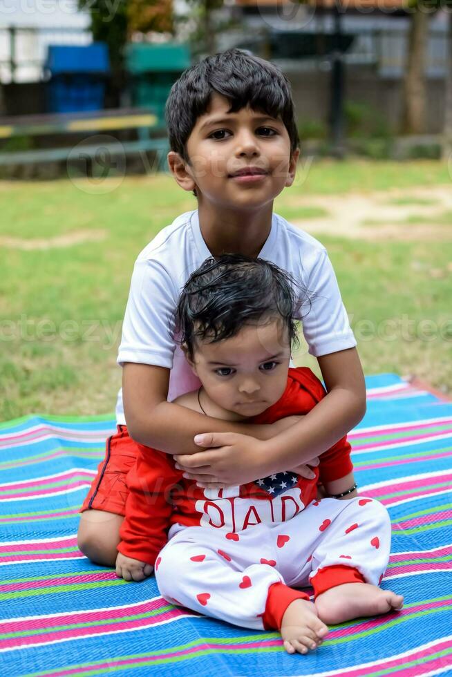 dos contento Niños en sociedad parque, contento asiático hermanos quien son sonriente felizmente juntos. hermanos jugar al aire libre en verano, mejor amigos. niñito bebé chico jugando con su contento hermano en el jardín foto