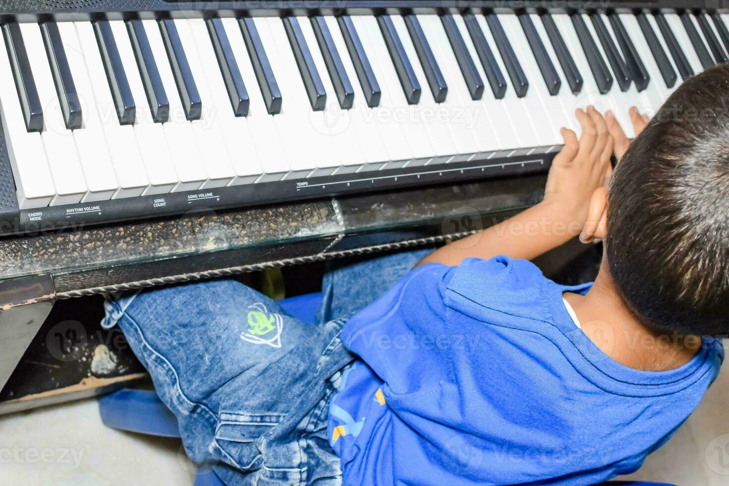Asian boy playing the synthesizer or piano. Cute little kid learning how to play piano. Child's hands on the keyboard indoor. photo