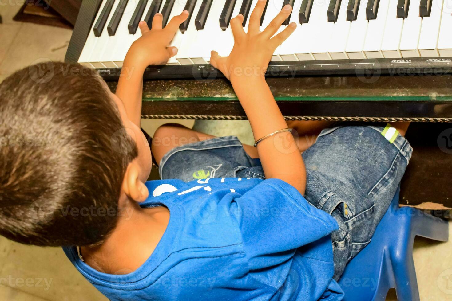 Asian boy playing the synthesizer or piano. Cute little kid learning how to play piano. Child's hands on the keyboard indoor. photo