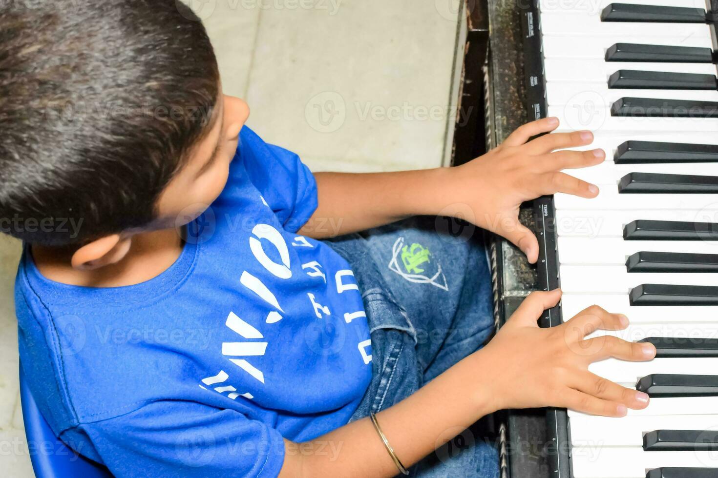 Asian boy playing the synthesizer or piano. Cute little kid learning how to play piano. Child's hands on the keyboard indoor. photo