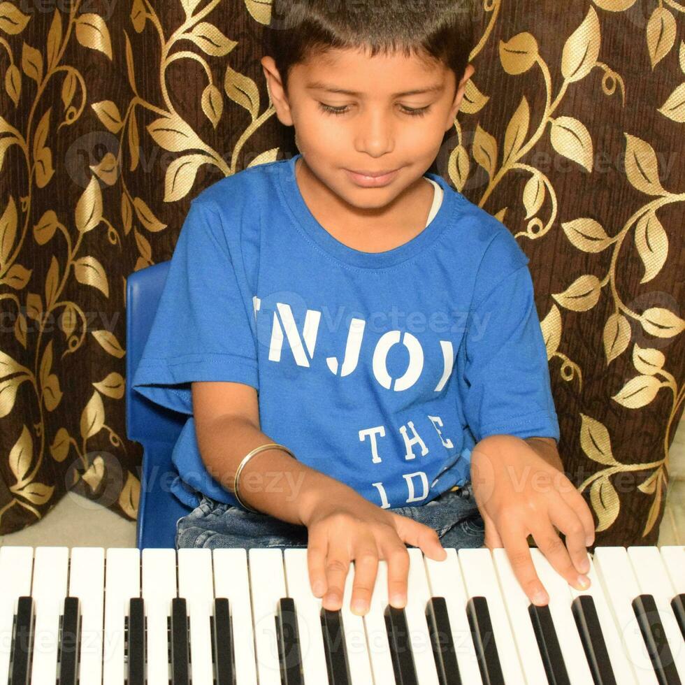Asian boy playing the synthesizer or piano. Cute little kid learning how to play piano. Child's hands on the keyboard indoor. photo