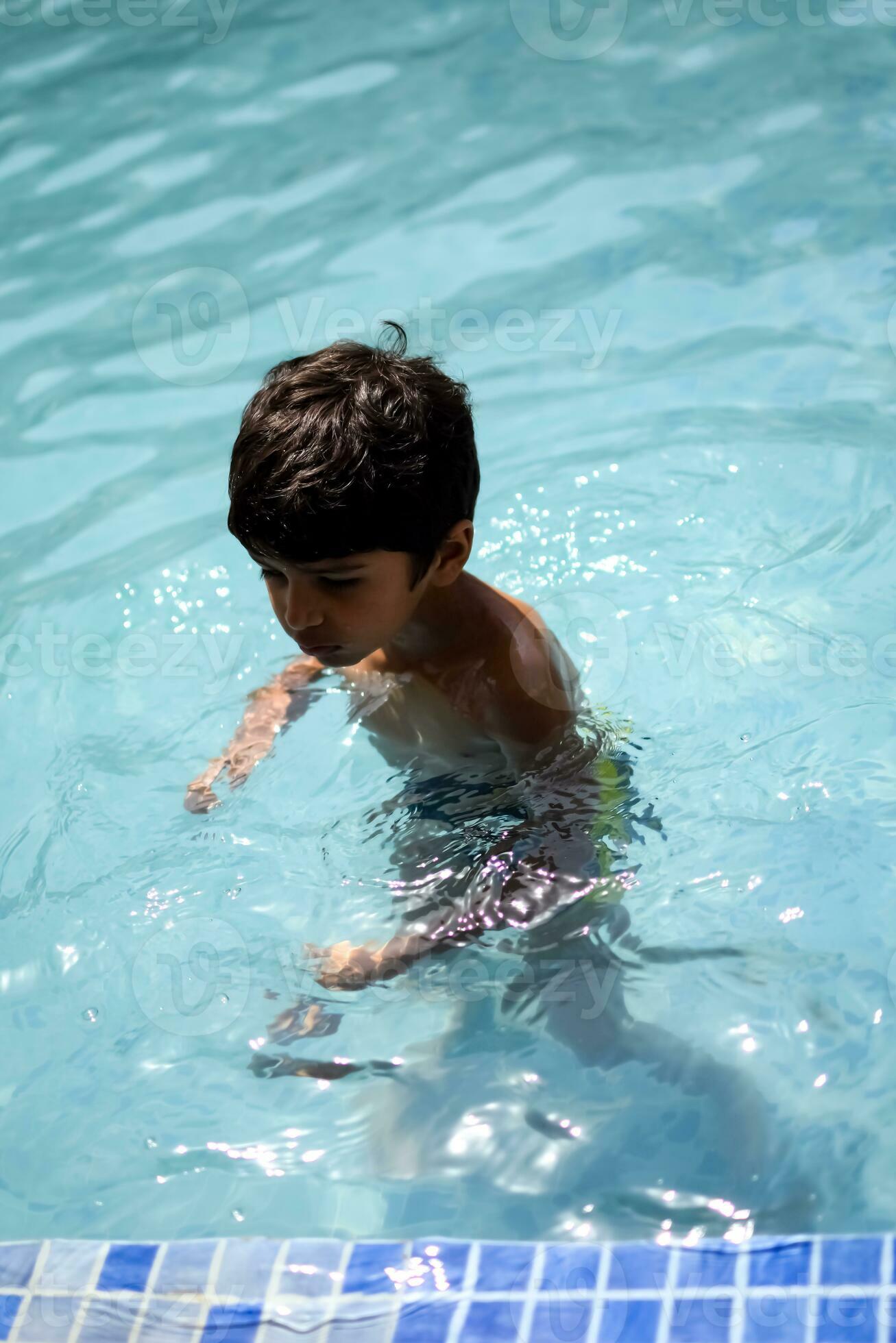 Happy Indian boy swimming in a pool, Kid wearing swimming costume along