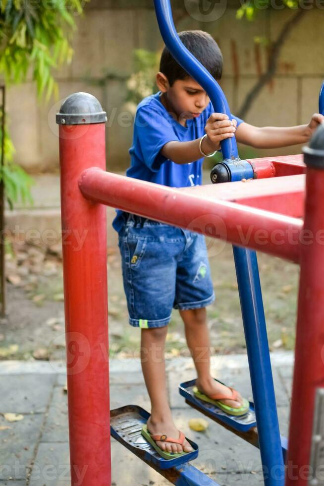 Asian boy doing routine exercise in society park during the morning time. Cute little kid exercise and gym to keep himself fit for life. Child's exercise outdoor shoot photo