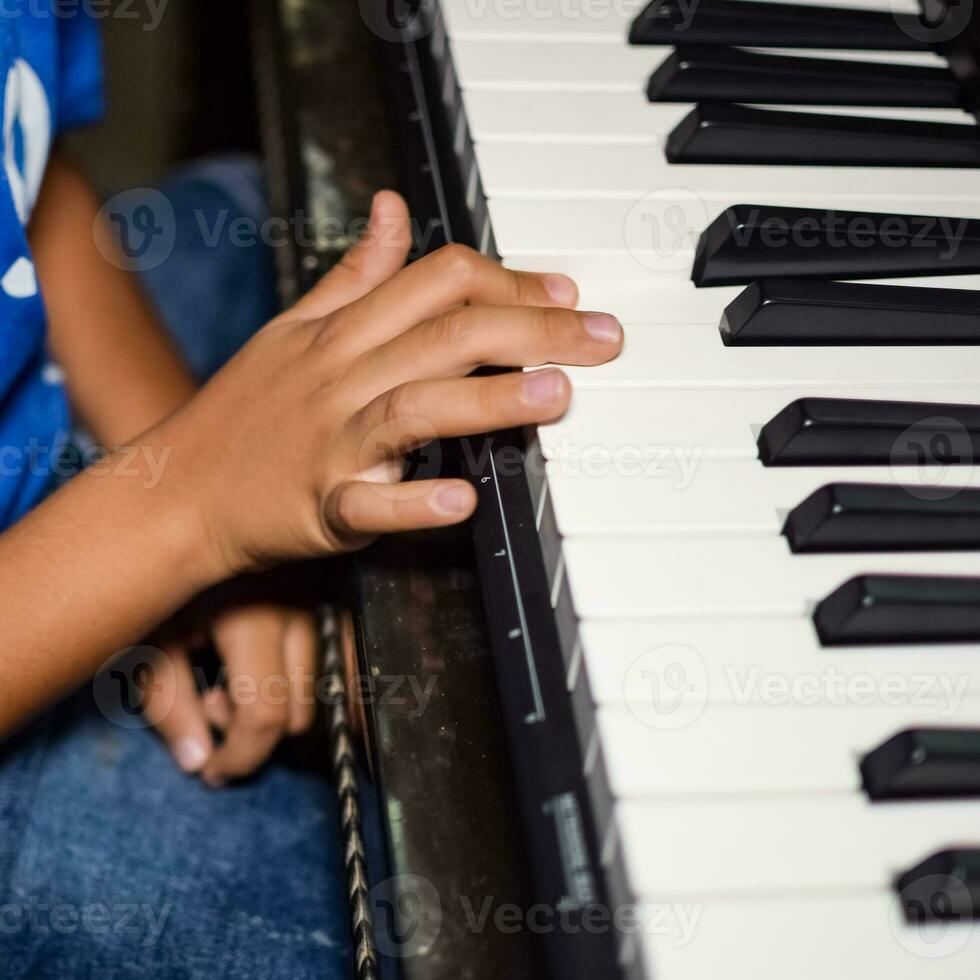 Asian boy playing the synthesizer or piano. Cute little kid learning how to play piano. Child's hands on the keyboard indoor. photo