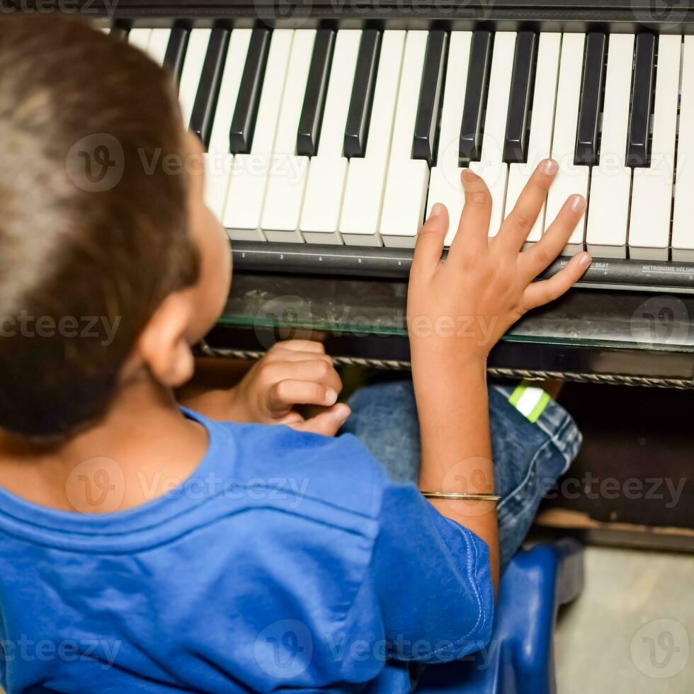 Asian boy playing the synthesizer or piano. Cute little kid learning how to play piano. Child's hands on the keyboard indoor. photo