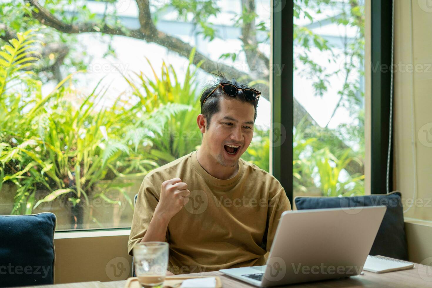 Lanza libre masculino sentado trabajando en el café y mirando fuera de foto