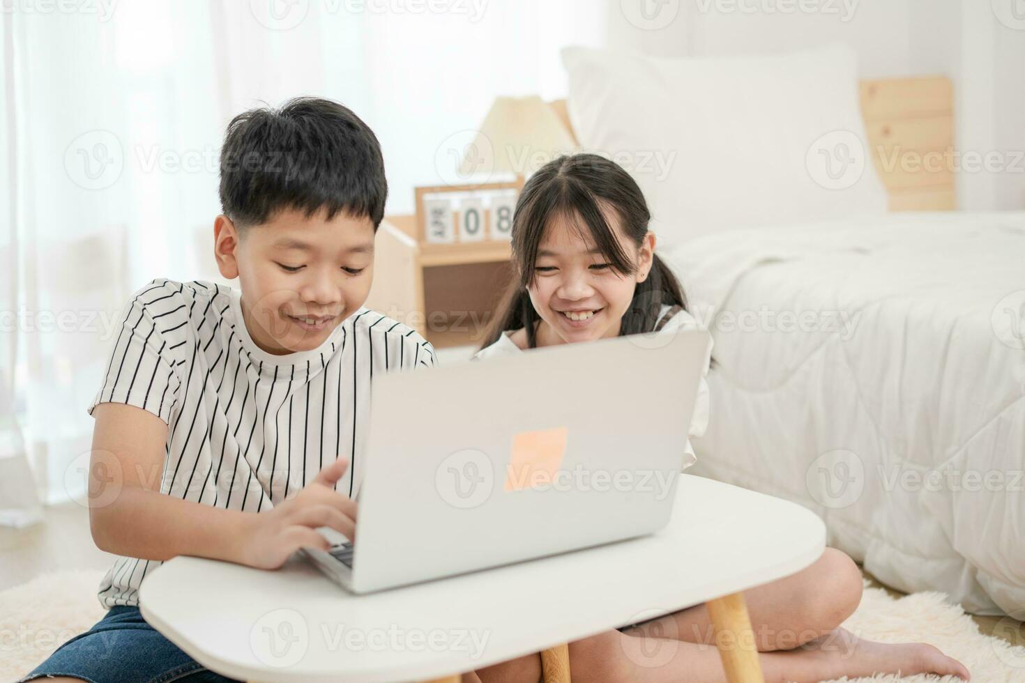 Asian brother and sister using laptop to learn at home photo