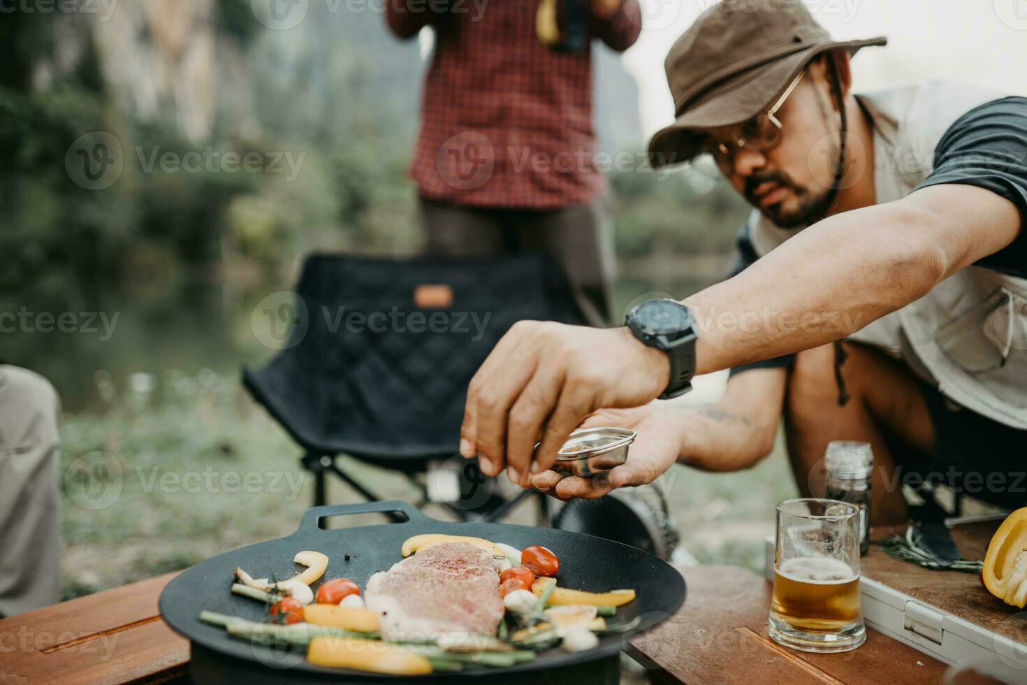Selective focus of male hand while cooking steak in camp photo