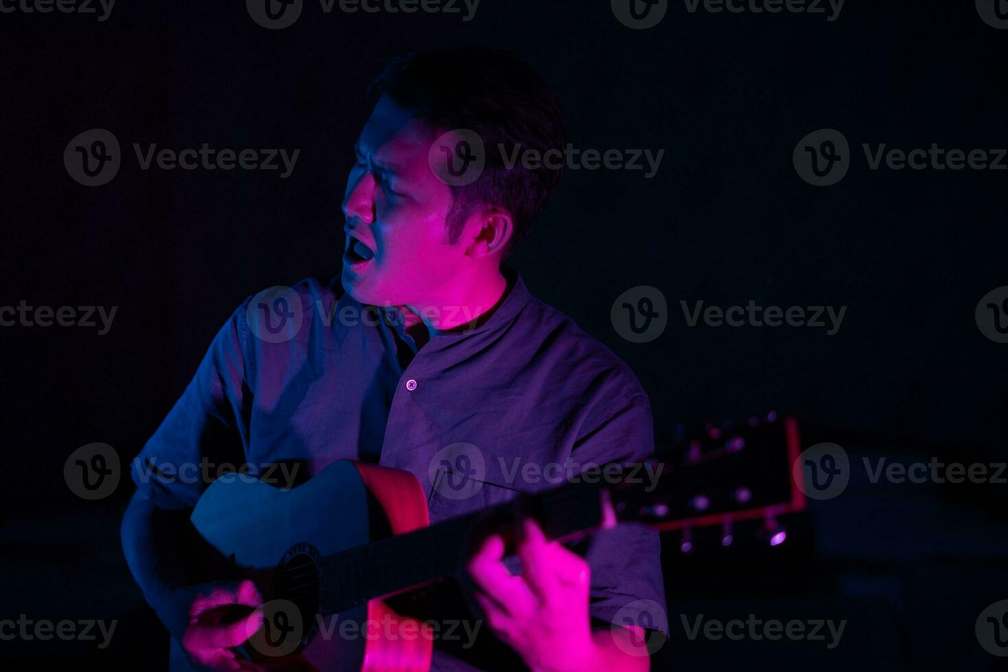 joven masculino cantante jugando guitarra y canto foto