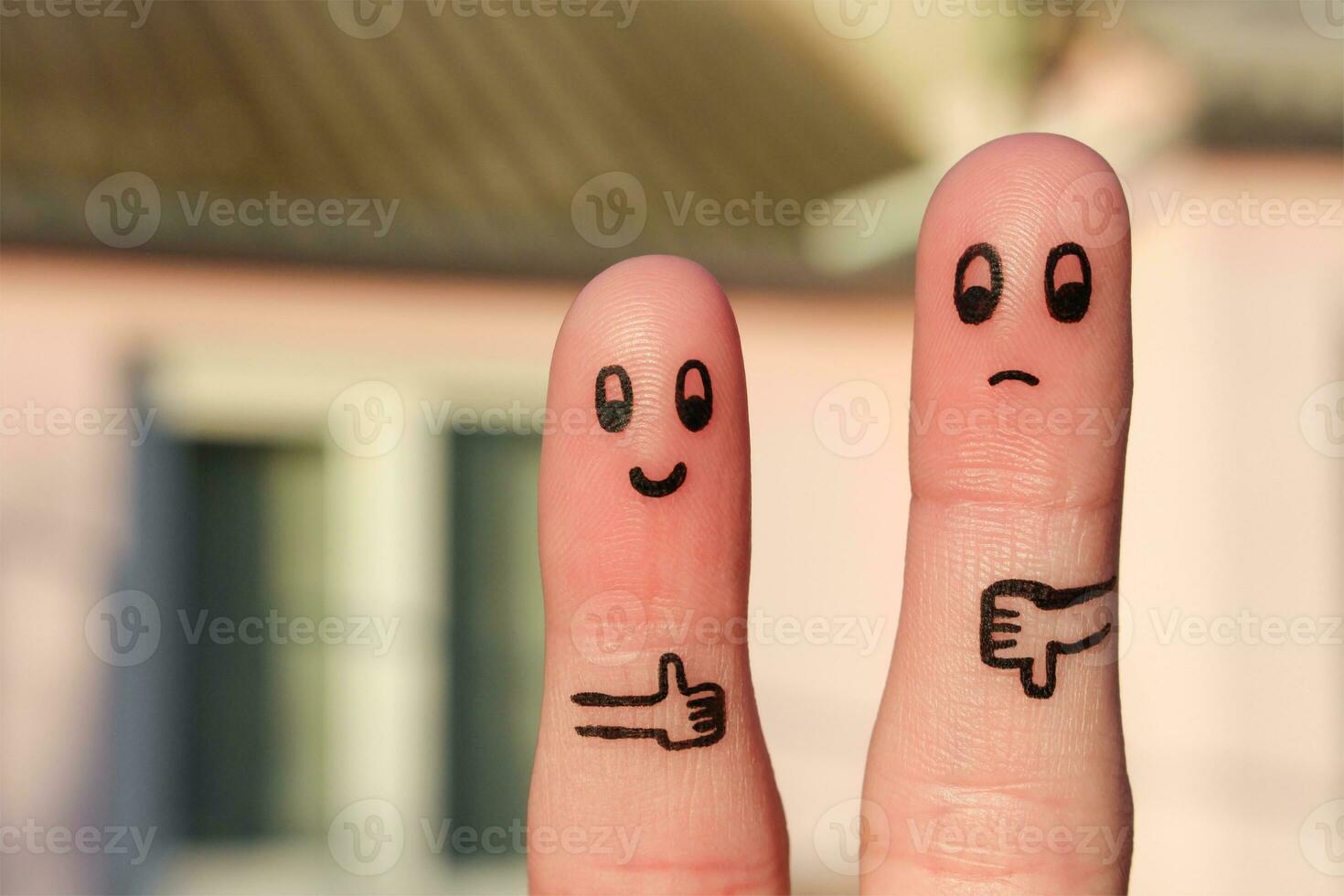 Finger art of couple. Woman showing thumbs up and man showing thumbs down. Concept of disagreement in family. photo