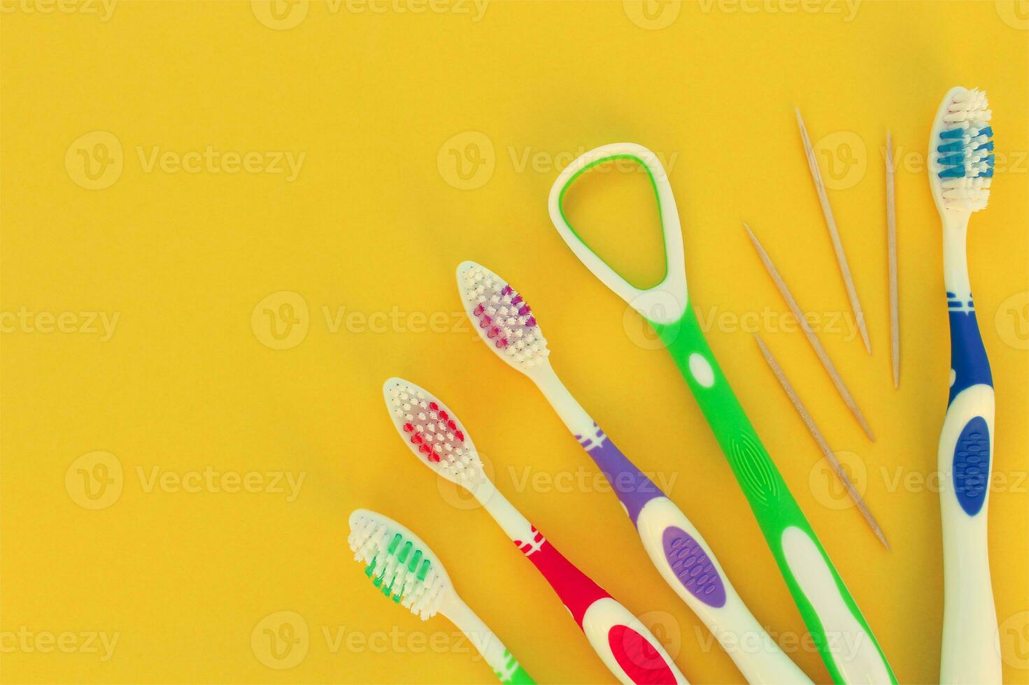 Toothbrushes, toothpick, tongue scraper on a yellow background. Top view. photo