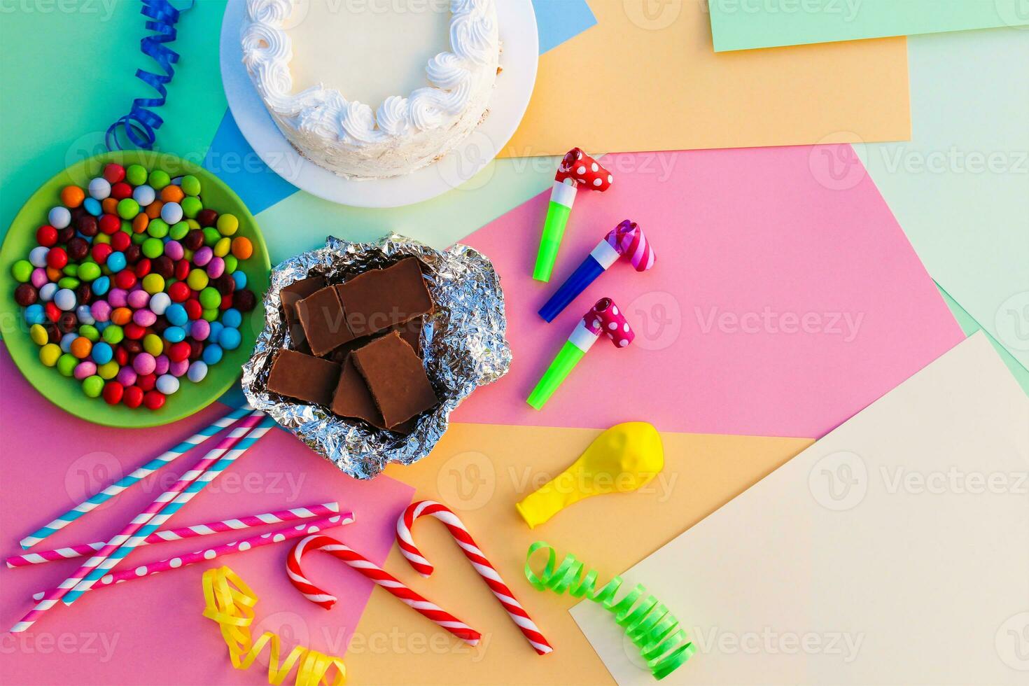 Cake, candy, chocolate, whistles, streamers, balloons on holiday table. Concept of children's birthday party. View top. photo