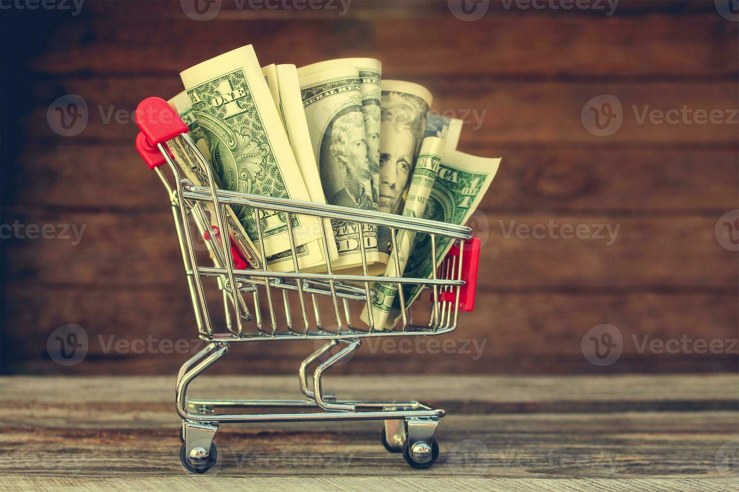 Shopping cart with money on old wood background. Toned image photo