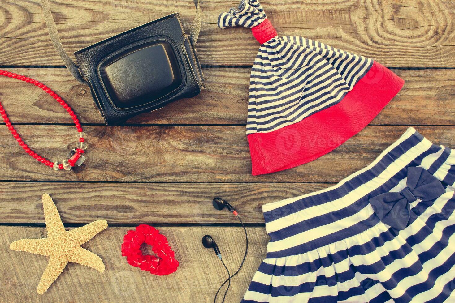 Summer children's clothing and beach accessories for your sea holiday on the old wooden background. Toned image. photo