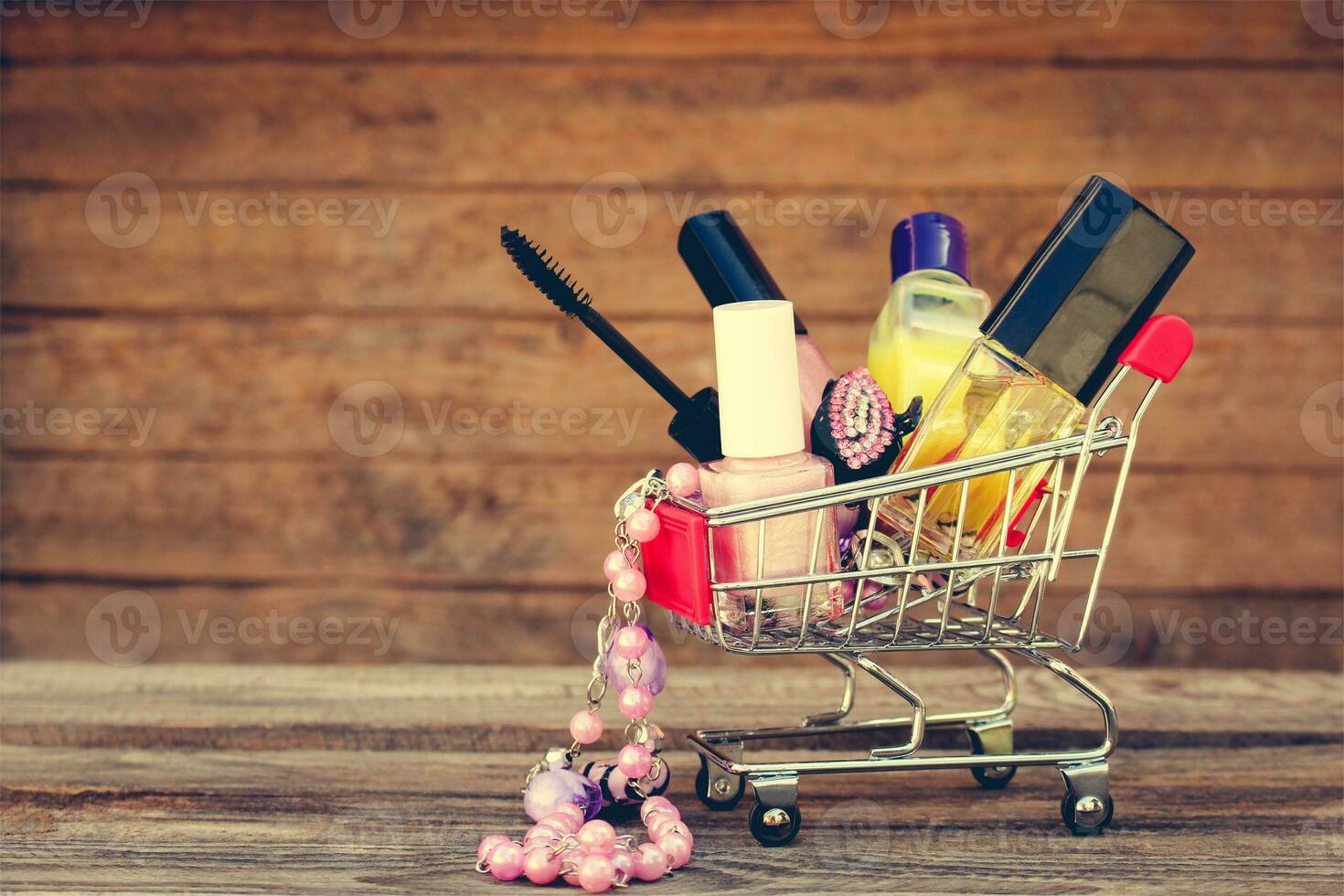 Shopping cart with cosmetics, beads on the old wood background. Toned image. photo