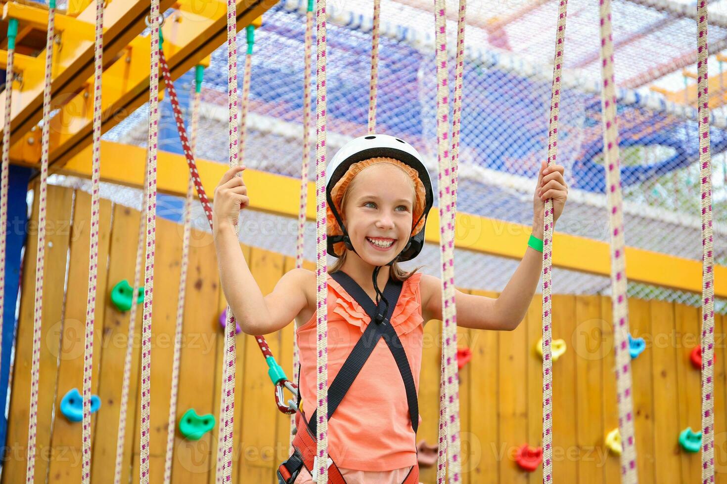 Happy girl on rope way in amusement center for children. photo